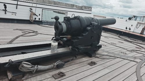 Kuvassa näkyy HMS Warriorin yläkannella keulassa (tai perässä) sijaitseva Armstrong 110-pounder -takalataustykki kuvattuna sen takaosasta. Tämä kuvakulma paljastaa erinomaisesti tykin historiallisen ja harvinaisen kierrelukon (screw breech).