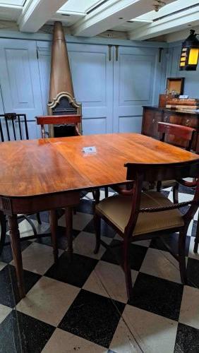 HMS Victoryn kapteenin ruokailusalonki (Captain's Dining Cabin).Tästä kuvakulmasta erottuu hienosti huoneen sydämenä toimiva mahonkinen jatkettava ruokapöytä tuoleineen sekä taustalla oleva tyylikäs valurautainen ja kuparipintainen kamina eli kamiina, jonka pitkä hormi johti savut suoraan yläkannelle.
